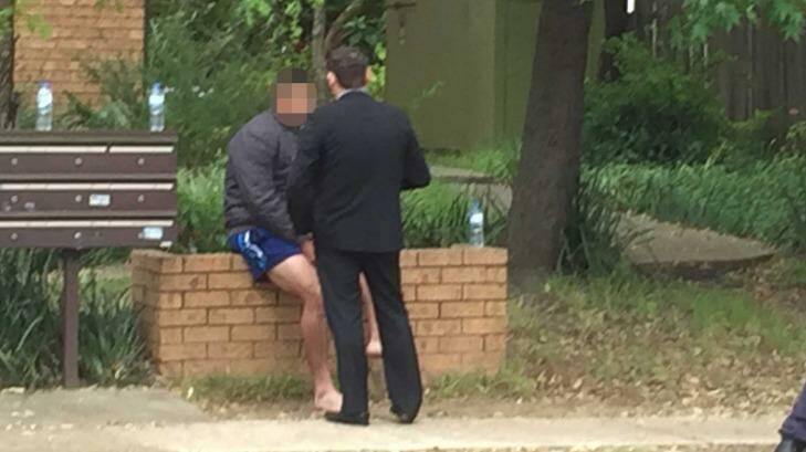Police raids: A man in blue shorts talks to a man in a suit outside a house at Lane Street, Wentworthville. Photo: Peter Rae