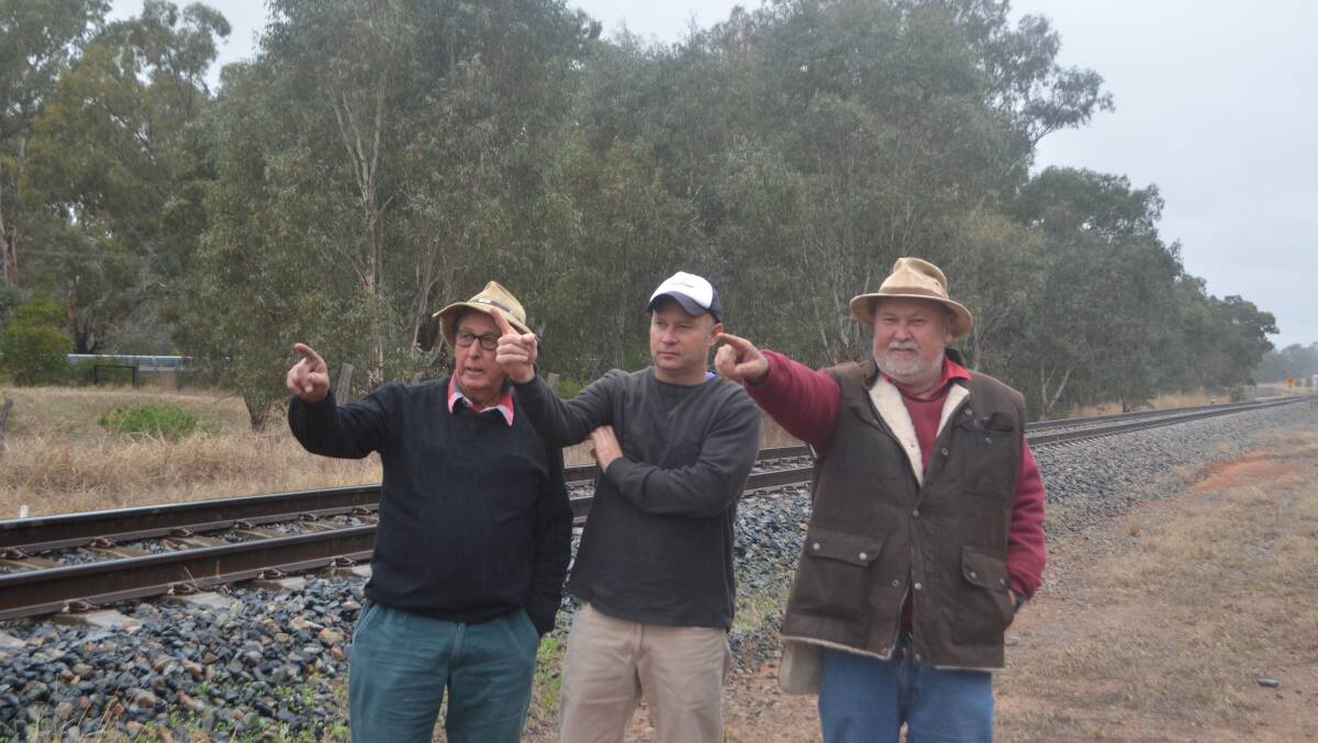 Landholders west of Cootamundra, Eric McKenzie, Tim Berryman and Tony Hill standing on the rail line near Stockinbingal, and pointing west indicating their preferred direction of the inland rail link through Narrandera.