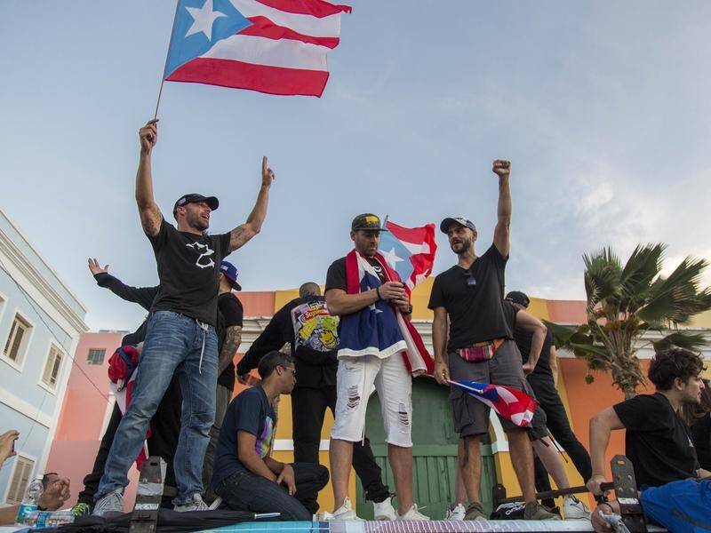 Singer Ricky Martin (L) waves the Puerto Rican flag at a rally against governor Ricardo Rosello.