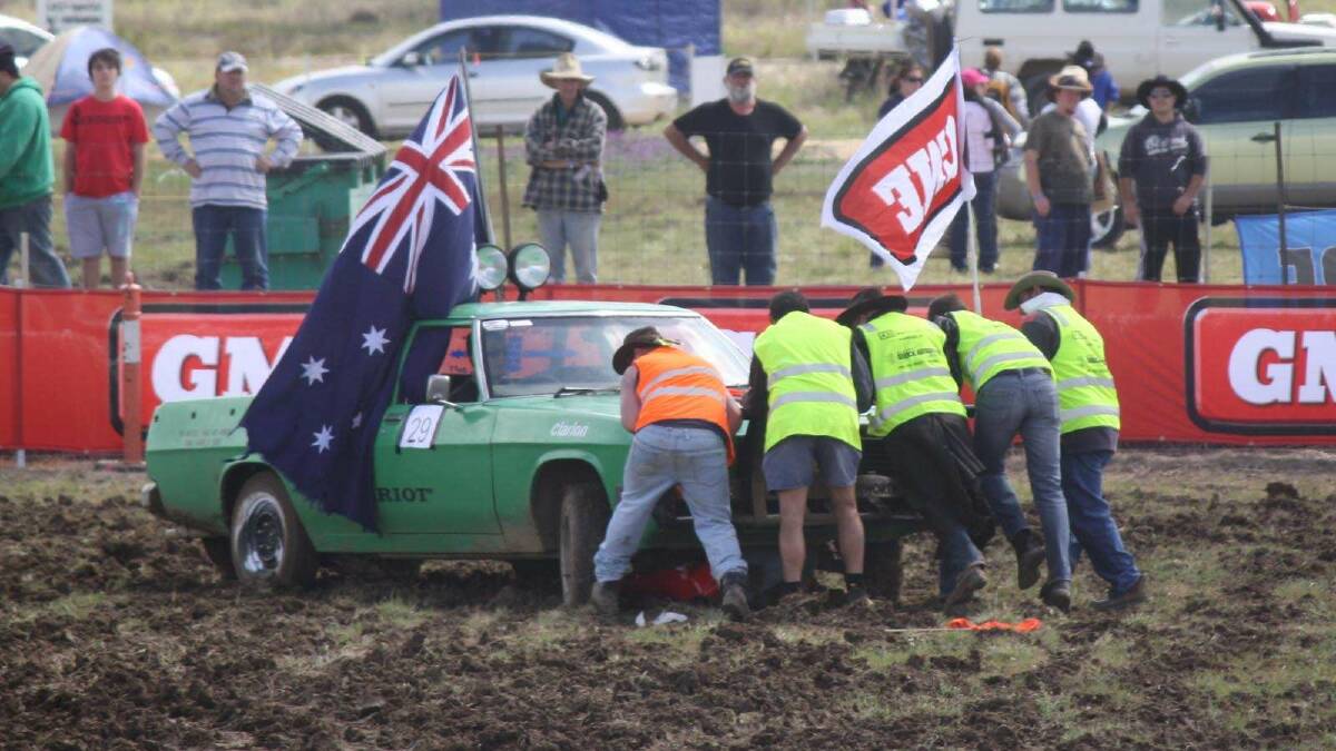 Volunteers remove a ute from a barrel in the ute barrel racing at the Deni Ute Muster in 2011.